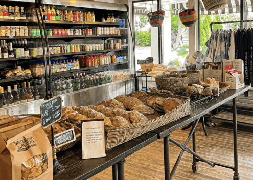 Baskets of fresh-baked bread on a table inside the market, with drinks and snacks on the shelves behind